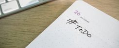 Close-up of a to-do list next to a computer keyboard on a desk.