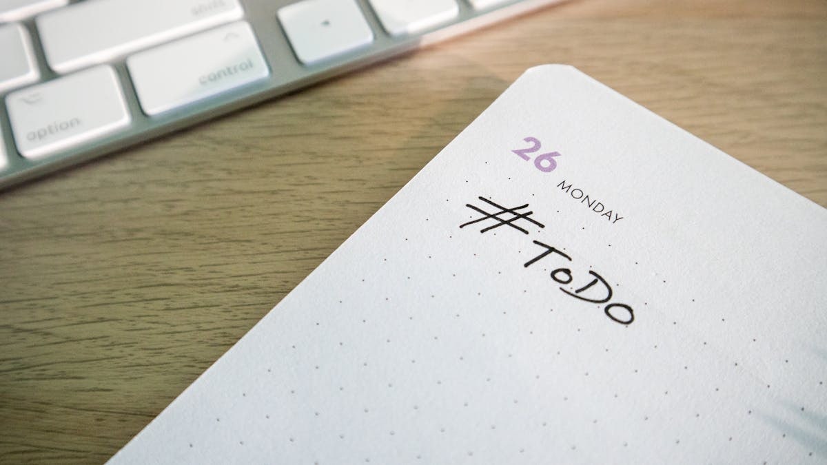 Close-up of a to-do list next to a computer keyboard on a desk.